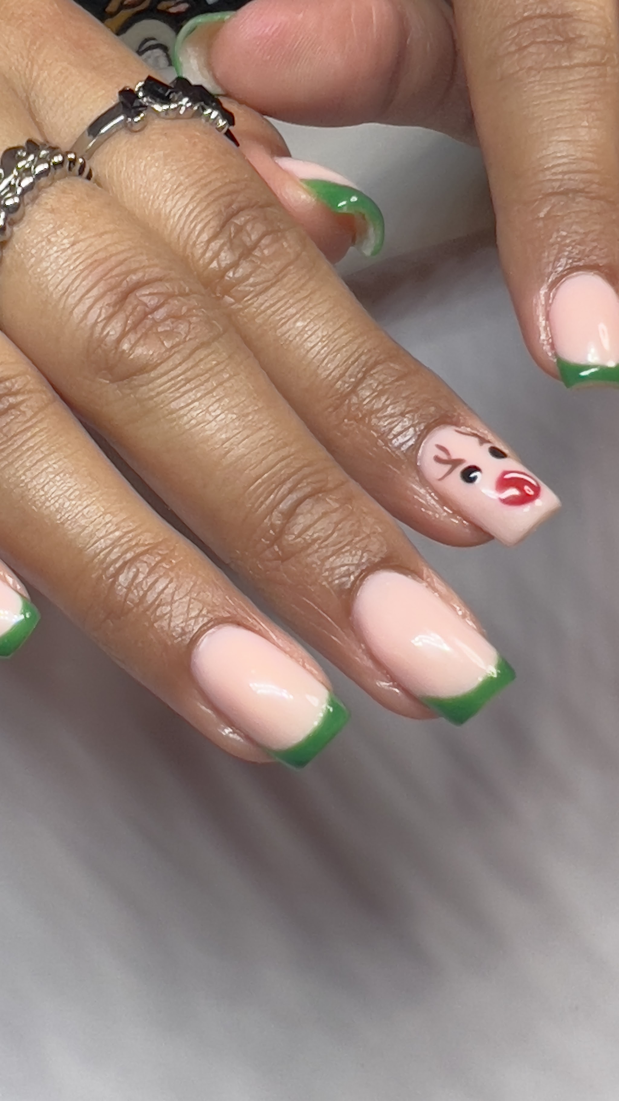 Nude nagels met groene French tips en een rood bloemetje als nail art