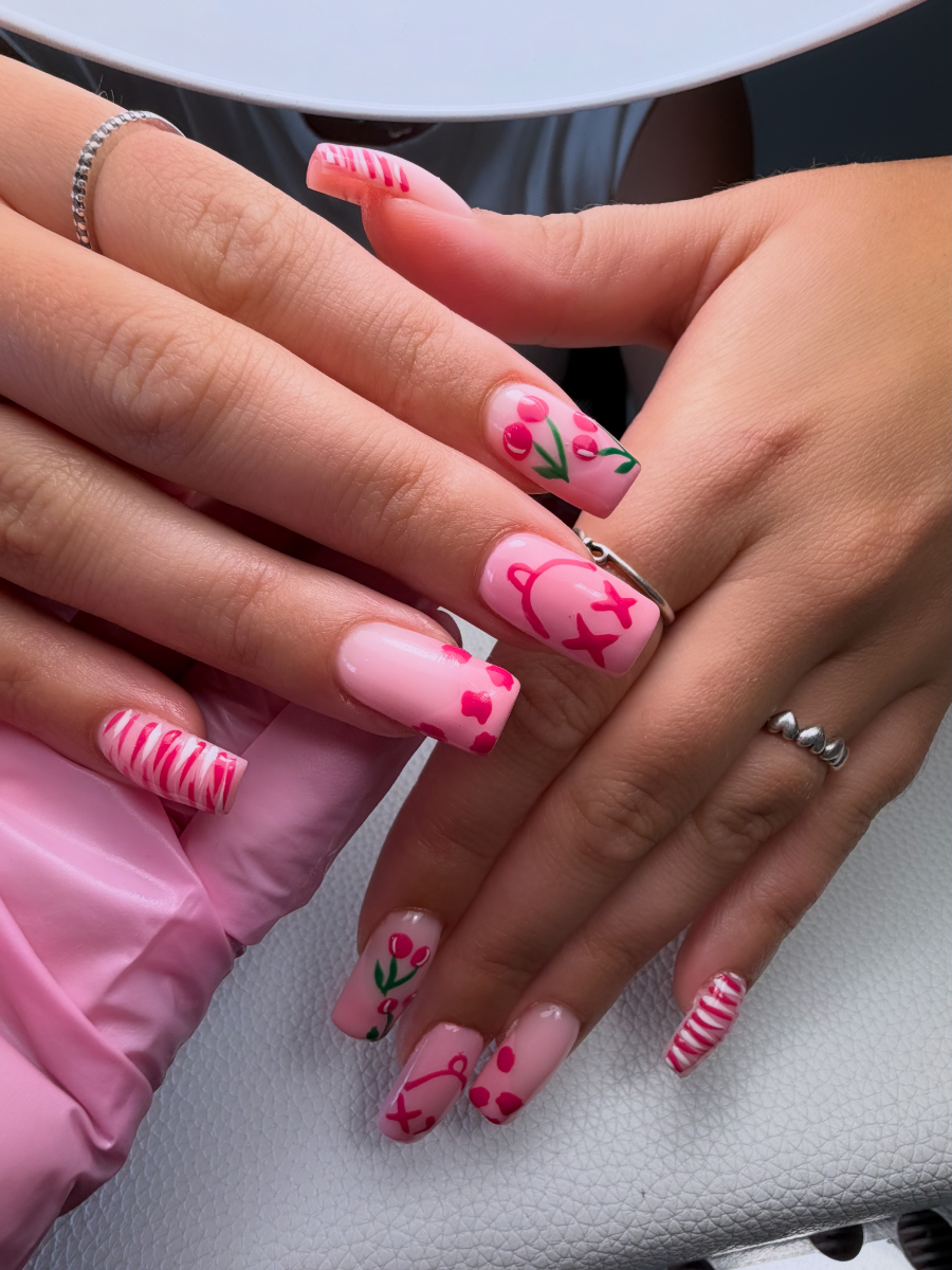 Roze nagels met kersjes, bloemen en streepjes als nail art